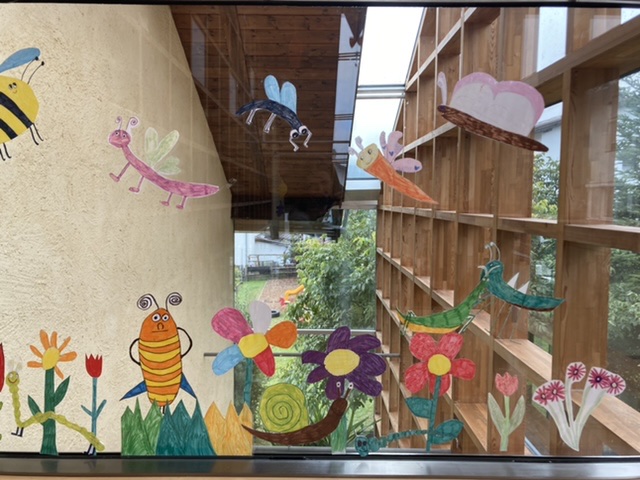 Fensterscheibe des Klimabündnismitglied Volksschule Telfes in Tirol bunt bemalt mit Blumen und Insekten