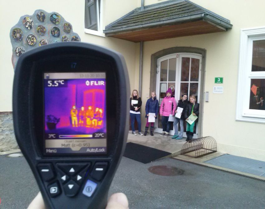 Sicht auf den Screen einer Wärmebildkamera, die Kinder vor dem Schultor zeigt