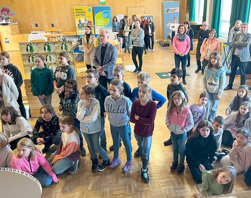 Eine Gruppe von Kindern, im Hintergrund Cornelia Schweiner und Stationen der Klimaversum Wanderausstellung