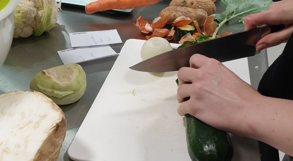 Hände schneiden eine Zucchini