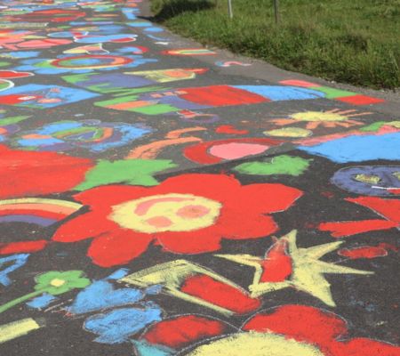 bunt bemalte Straße in Nahaufnahme, am Wegrand Gras